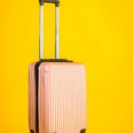 Pink color luggage or baggage bag use for transportation travel and leisure on yellow isolated background